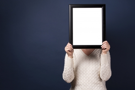 mature woman is covering her face with a picture frameの写真素材