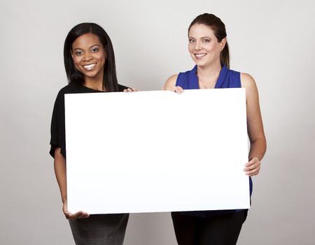 two women holding white board on light grey backgroundの写真素材