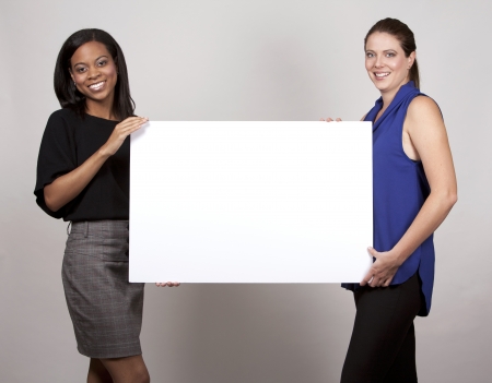 two women holding white board on light grey backgroundの写真素材