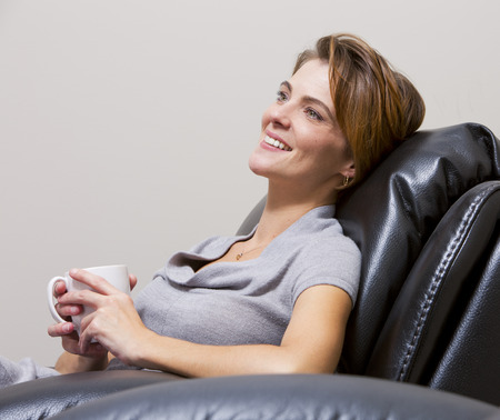 caucasian woman sitting in the living room drinking coffeeの写真素材