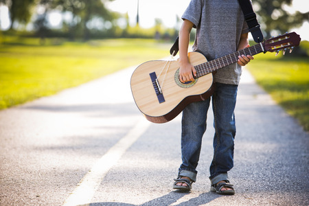 cuacasian boy with guitar in the park outdoorsの写真素材