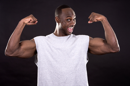young fitness black man wearing light tshirt on dark backgroundの写真素材
