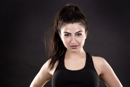 pretty brunette wearing fitness outfit on dark black backgroundの写真素材