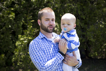 young father holding one yeard old baby son outdoorsの写真素材