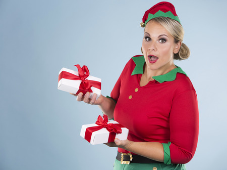 blonde woman wearing elf christmas costume on blue backgroundの写真素材
