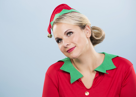 blonde woman wearing elf christmas costume on blue backgroundの写真素材