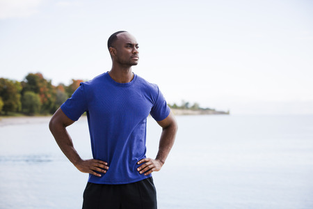 young black man wearing athletic wear on the beachの写真素材
