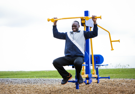 Active black man in training suit exercising at outdoor gymの写真素材