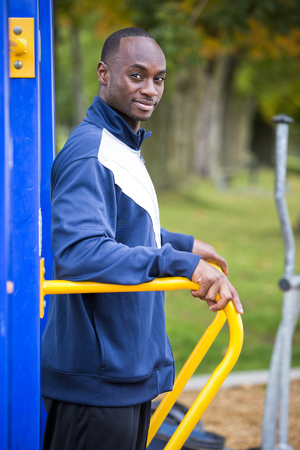 Active black man in training suit exercising at outdoor gymの写真素材