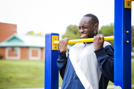 Active black man in training suit exercising at outdoor gymの写真素材