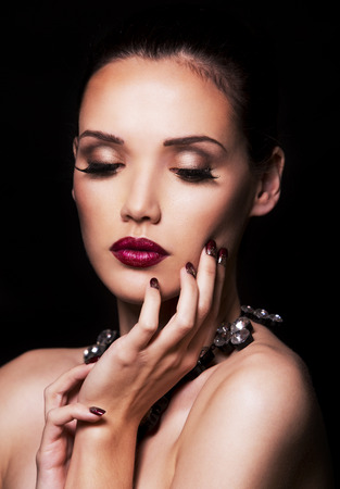 beautiful woman with dark makeup and purple lipstick posing on black backgroundの写真素材