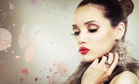 Upscale woman wearing gold jewellery and red lipstick on light backgroundの写真素材
