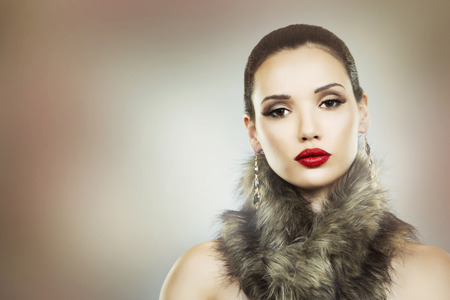 Upscale woman wearing gold jewellery and red lipstick on light backgroundの写真素材