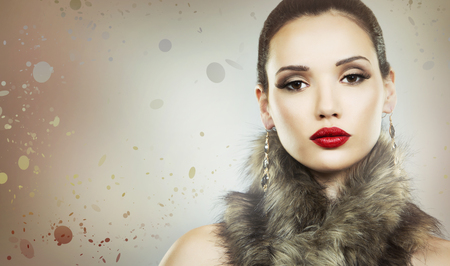 Upscale woman wearing gold jewellery and red lipstick on light backgroundの写真素材