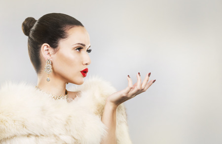Upscale woman wearing gold jewellery and red lipstick on light backgroundの写真素材
