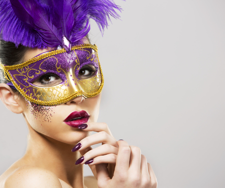 beautiful woman with dramatic mekaup and pruple lipstick wearing puprle mask. Light background. Golden.の写真素材