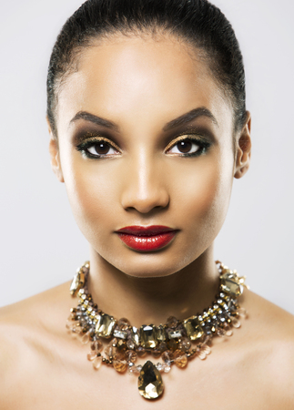 Upscale Indian woman wearing gold jewellery and red lipstick on light backgroundの写真素材