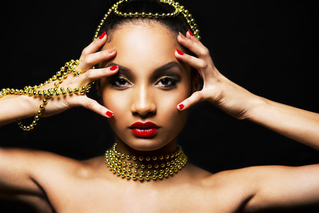 Upscale Indian woman wearing gold jewellery and red lipstick on black backgroundの写真素材