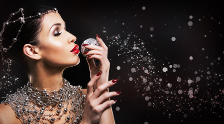 beautiful woman with dark makeup and red lipstick posing on black background. Wearing silver disco ball jewllery.の写真素材