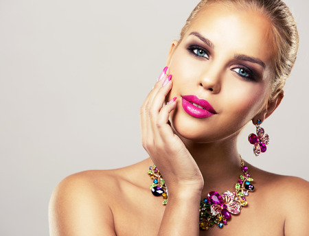 beautiful woman with dark makeup and pink lipstick posing on light background wearing flower spring and summer jewellry necklaceの写真素材