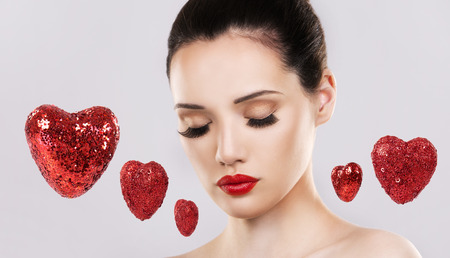 beautiful woman with dark makeup and red lipstick posing on light grey background. Valentines day love hearts.の写真素材