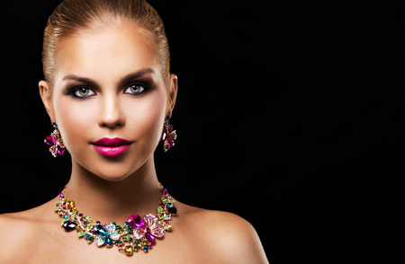 beautiful woman with dark makeup and pink lipstick posing on black background wearing flower spring and summer jewellry necklaceの写真素材