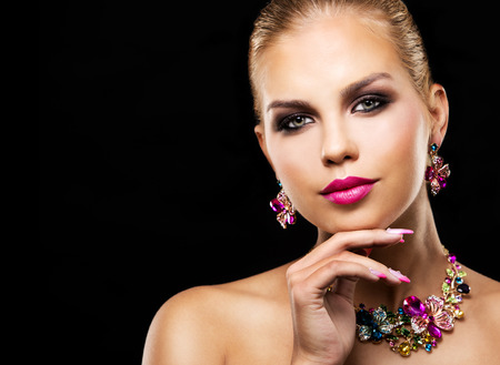 beautiful woman with dark makeup and pink lipstick posing on black background wearing flower spring and summer jewellry necklaceの写真素材