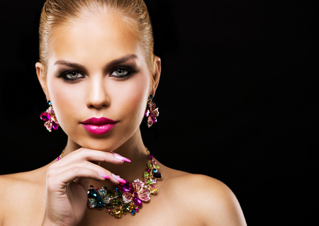 beautiful woman with dark makeup and pink lipstick posing on black background wearing flower spring and summer jewellry necklaceの写真素材