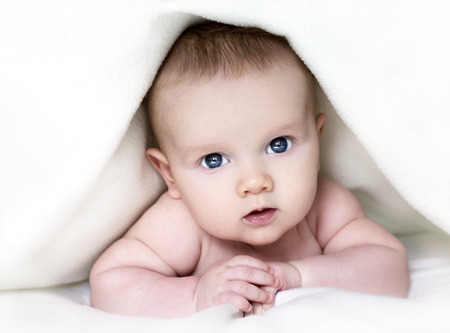baby boyl is hiding under the white blanketの写真素材