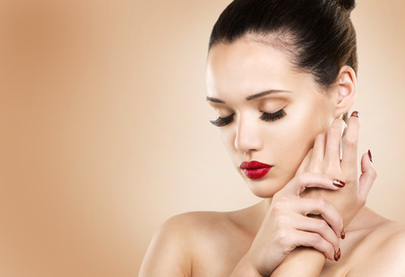 beautiful woman with dark makeup and red lipstick posing on light beige backgroundの写真素材