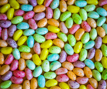 arrangement of colorful easter jelly bean eggs laid on sack textureの写真素材