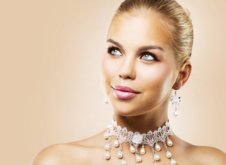 beautiful woman with dark makeup and pink lipstick posing on light background wearing bridal spring and summer jewellry necklaceの写真素材