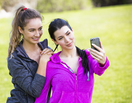 young fit caucasian women wearing active wear holding phone and taking selfieの写真素材