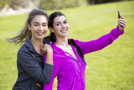 young fit caucasian women wearing active wear holding phone and taking selfieの写真素材