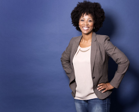 beautiful casual black woman wearing jacket and jeans on dark blue backgroundの写真素材
