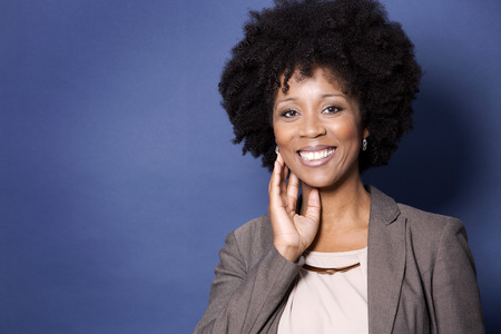 beautiful casual black woman wearing jacket and jeans on dark blue backgroundの写真素材