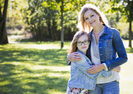 young family, mother and daughter wearing casual outfits, outdoors in the parkの写真素材