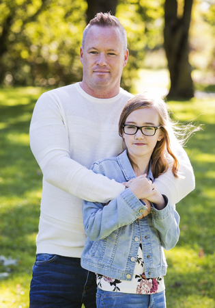 young family, father and daughter wearing casual outfits, outdoors in the parkの写真素材