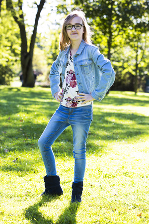 young teenager is wearing jeans, posing outdoors in the parkの写真素材