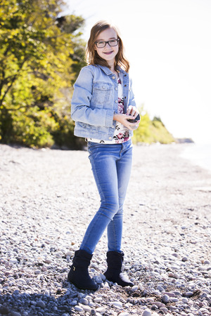 young teenager is wearing jeans, posing outdoors on the beachの写真素材