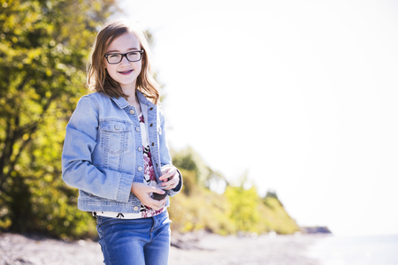 young teenager is wearing jeans, posing outdoors on the beachの写真素材