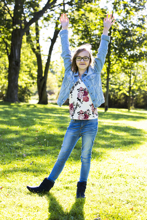 young teenager is wearing jeans, posing outdoors in the parkの写真素材