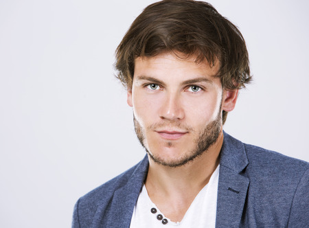 Fashion portrait of a handsome man with trendy hairstyle in a stylish jacket on light backgroundの写真素材