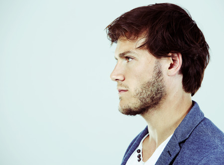 Fashion portrait of a handsome man with trendy hairstyle in a stylish jacket on light backgroundの写真素材