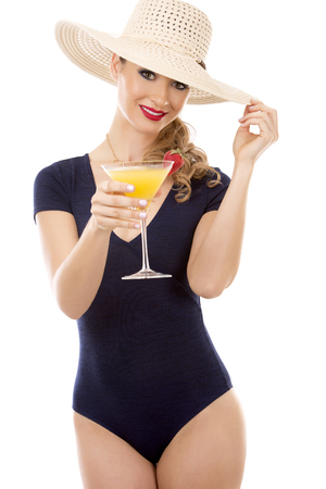 beautiful woman with dark makeup and red lipstick posing on white background wearing bright blue swimsuit and hat. Holding drink. の写真素材