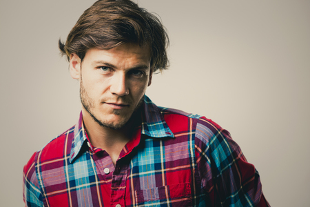 Fashion portrait of a handsome man with trendy hairstyle in a stylish shirt on light green backgroundの写真素材