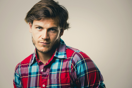 Fashion portrait of a handsome man with trendy hairstyle in a stylish shirt on light green backgroundの写真素材