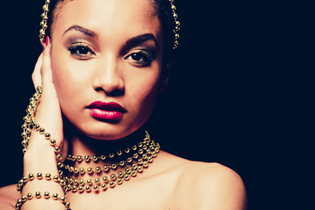 Upscale Indian woman wearing gold jewellery and red lipstick on dark backgroundの写真素材