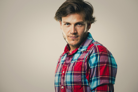 Fashion portrait of a handsome man with trendy hairstyle in a stylish shirt on light green backgroundの写真素材