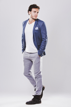 Fashion portrait of a handsome man with trendy hairstyle in a stylish jacket on light backgroundの写真素材